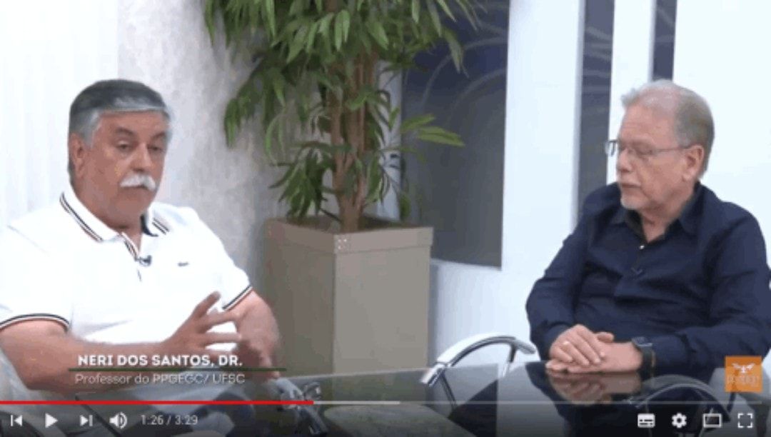 Dois homens estão sentados à mesa conversando.