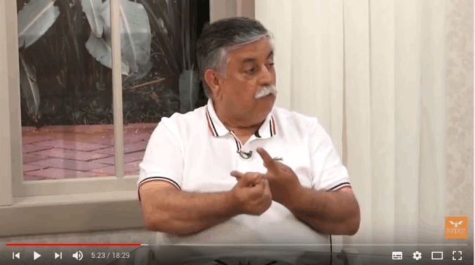 Um homem de camisa branca está sentado em frente a uma janela